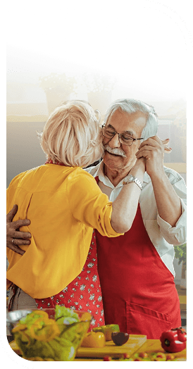 Elderly Couple in Aprons Dancing Together in the Kitchen in Independent Living