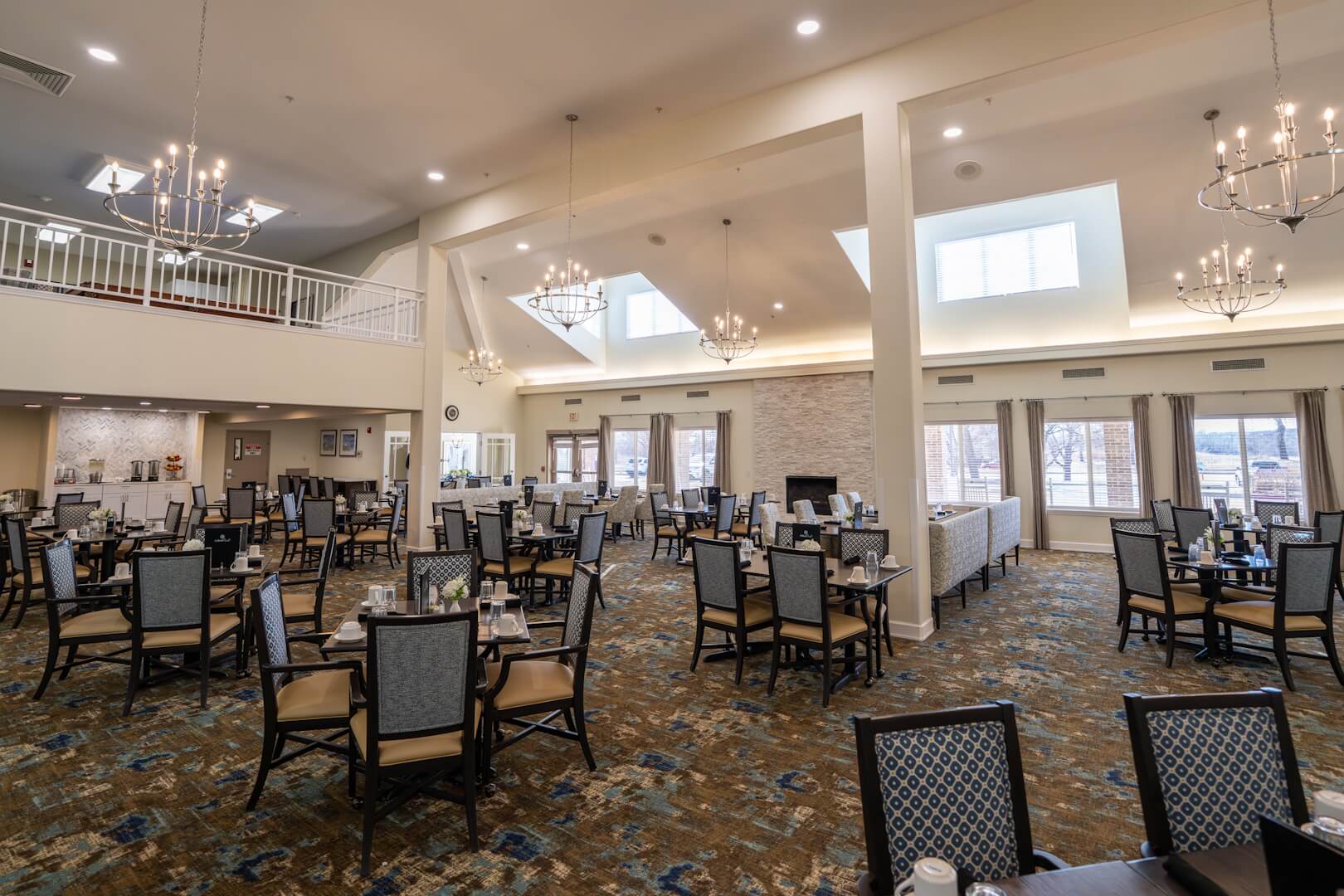 Spacious Chandelier-Lit Dining Room with Stone Fireplace at an Independent Living Community