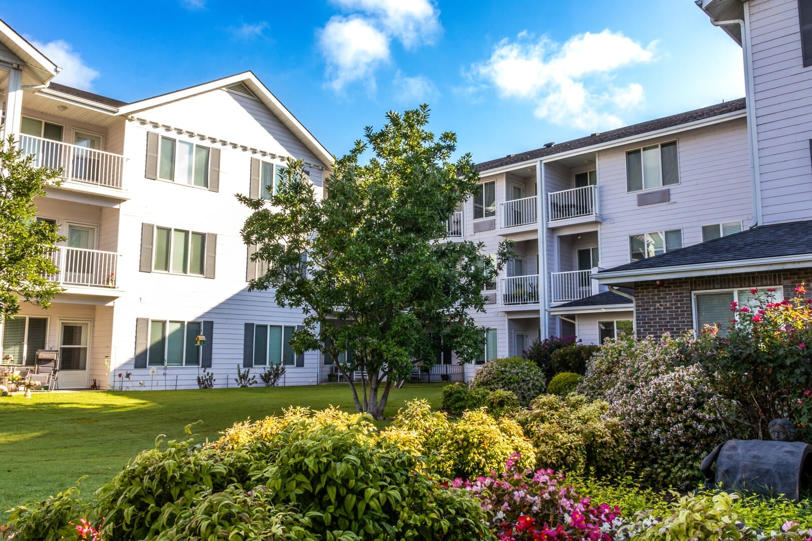 Bright Courtyard Garden with Blooming Shrubs and Resident Balconies at an Independent Living Community