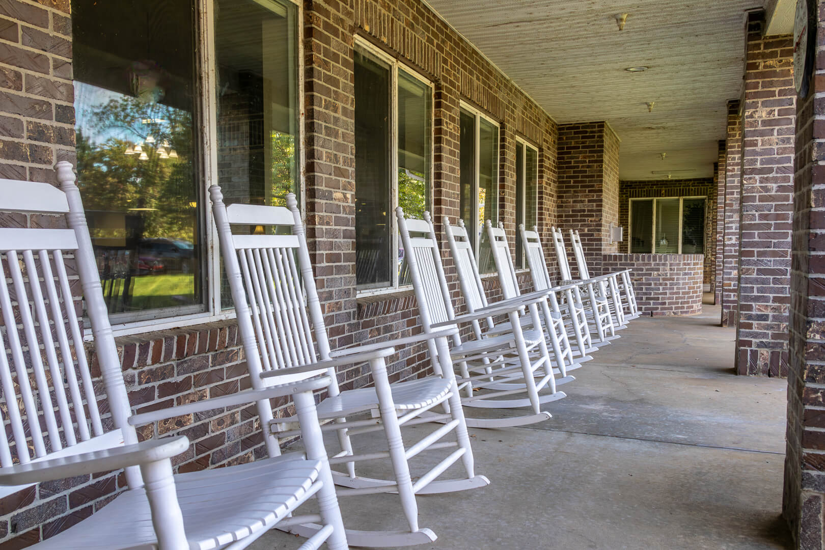 Row of White Rocking Chairs on a Brick Porch at an Independent Living Community