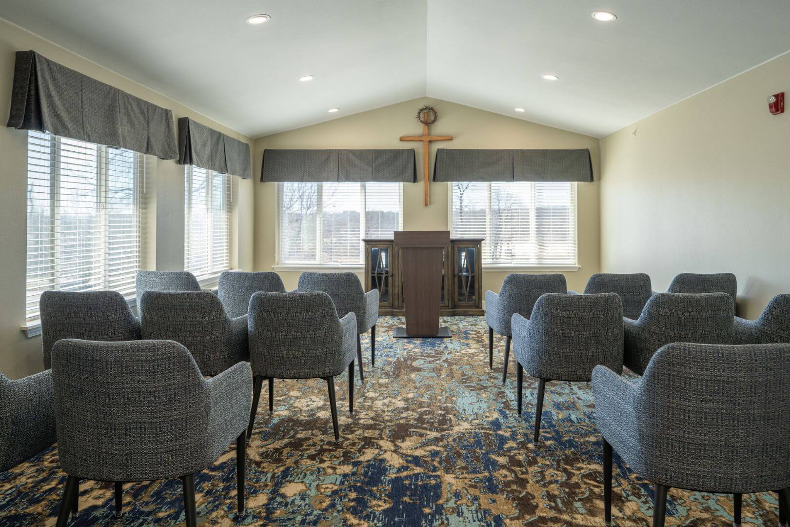 Intimate Chapel Room with Crucifix and Gray Armchairs at an Independent Living Community