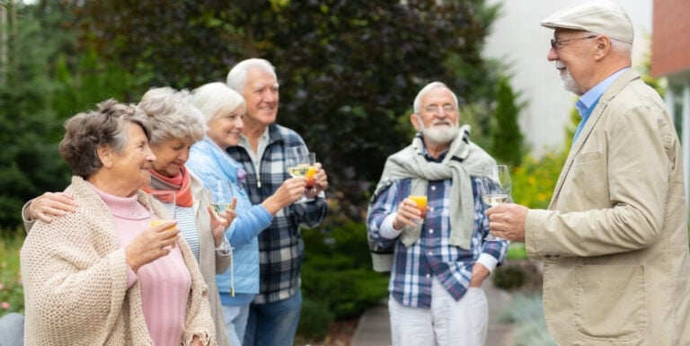 Elderly Friends Toasting Drinks Outdoors at Independent Living Facility