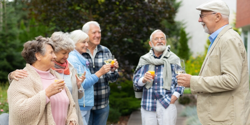 Elderly Friends Toasting Drinks Outdoors at Independent Living Facility